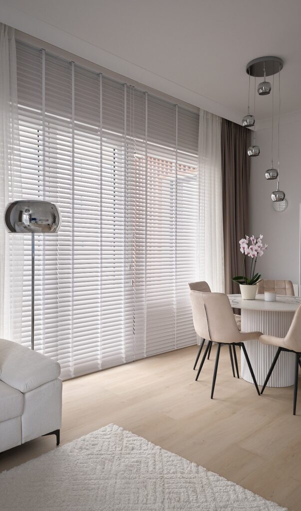 zaluzje drewniane biale z zaslonami w salonie z jadalnia